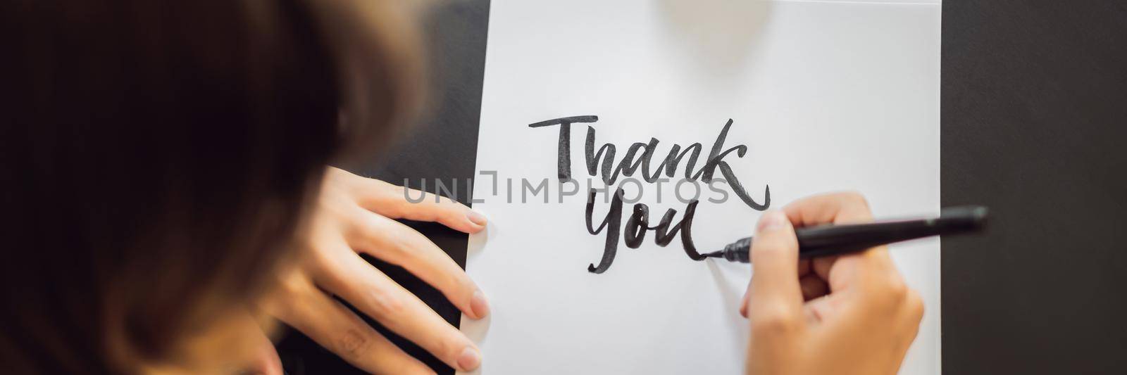 BANNER, LONG FORMAT Thank you. Calligrapher Young Woman writes phrase on white paper. Inscribing ornamental decorated letters. Calligraphy, graphic design, lettering, handwriting, creation concept.