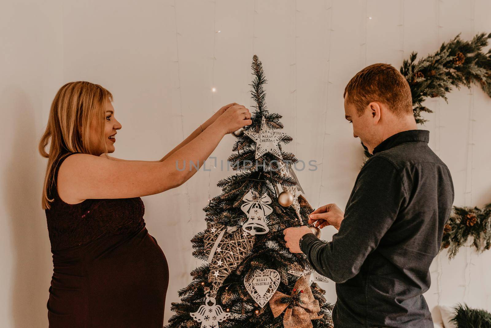 family with pregnant wife decorates the house for the New Year by AndriiDrachuk