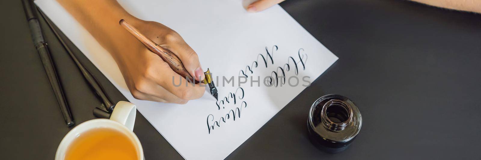 BANNER, LONG FORMAT Calligrapher Young Woman writes phrase on white paper. Inscribing ornamental decorated letters. Calligraphy, graphic design, lettering, handwriting, creation concept by galitskaya