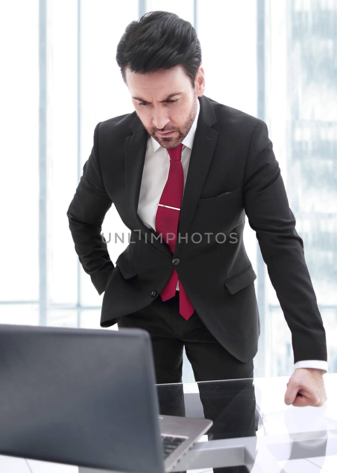 Businessman standing at his Desk and looking at the laptop screen.people and technology