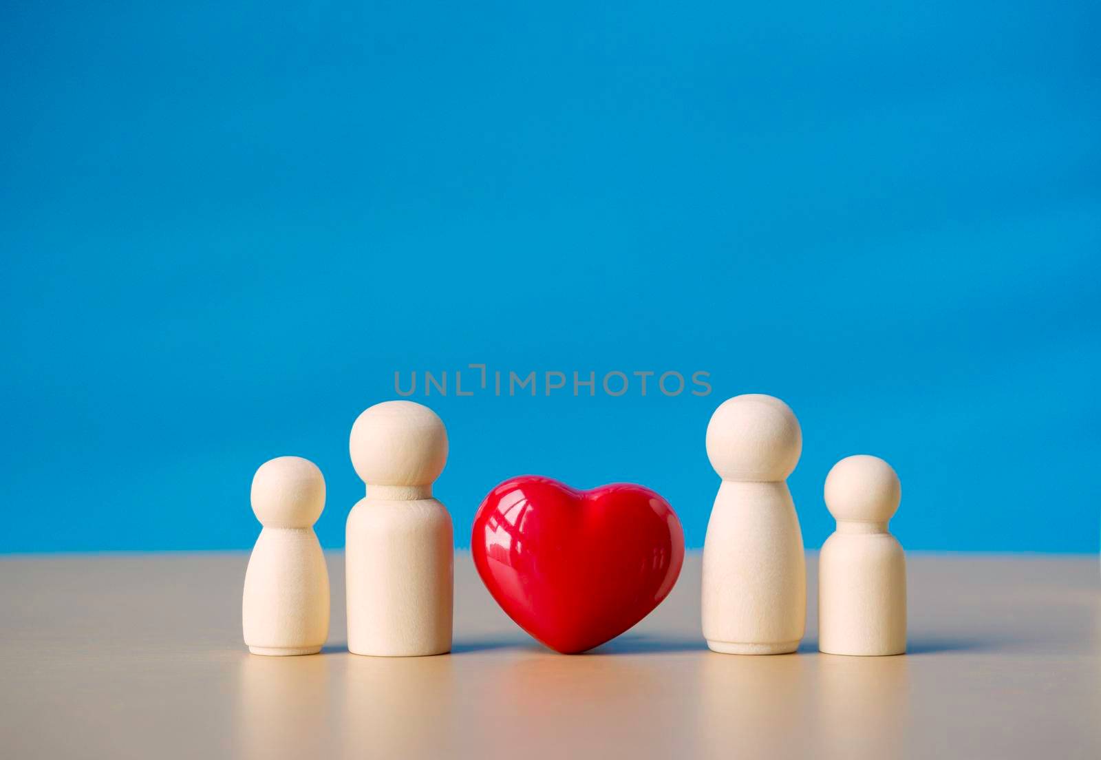 Family wooden figure standing near red heart symbol. Concept of love of relationship family, couple life and happiness with blue background.