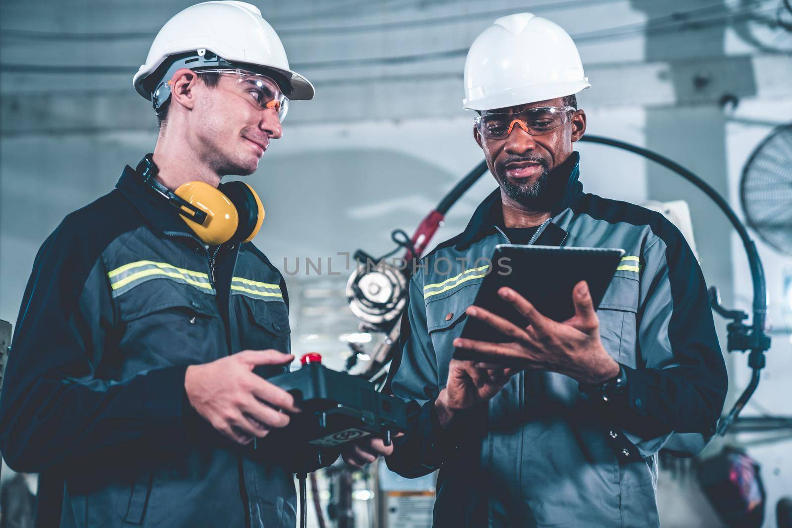 Group of factory job workers using adept machine equipment in a workshop by biancoblue