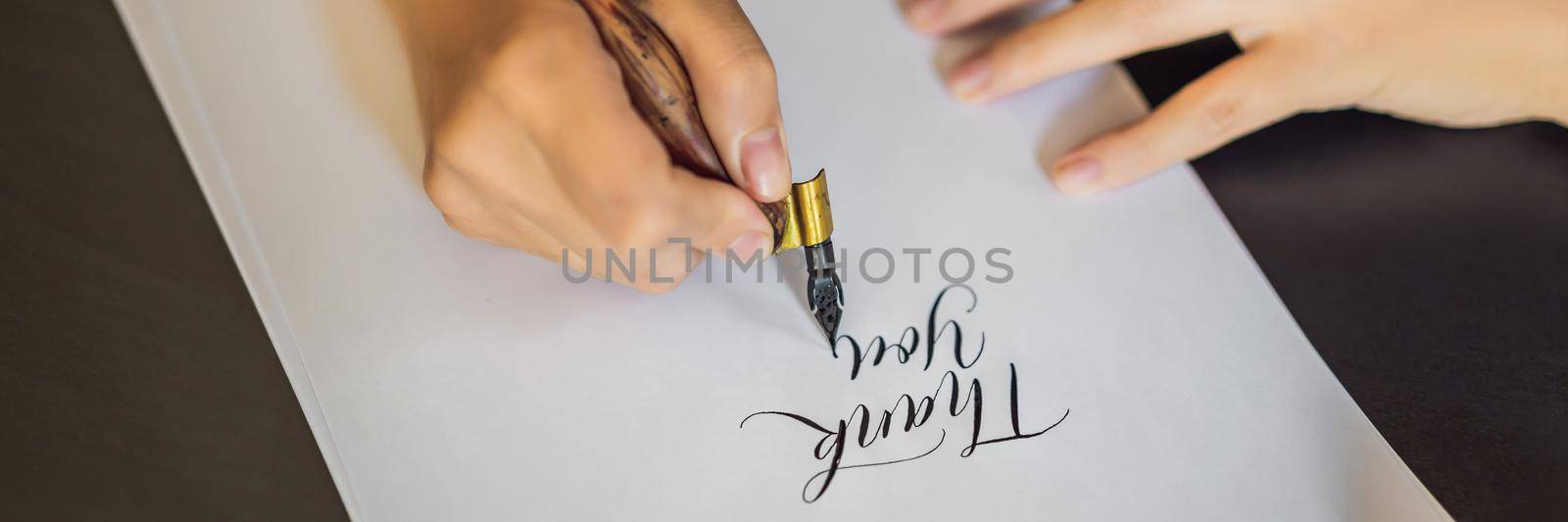 BANNER, LONG FORMAT Thank you. Calligrapher Young Woman writes phrase on white paper. Inscribing ornamental decorated letters. Calligraphy, graphic design, lettering, handwriting, creation concept by galitskaya