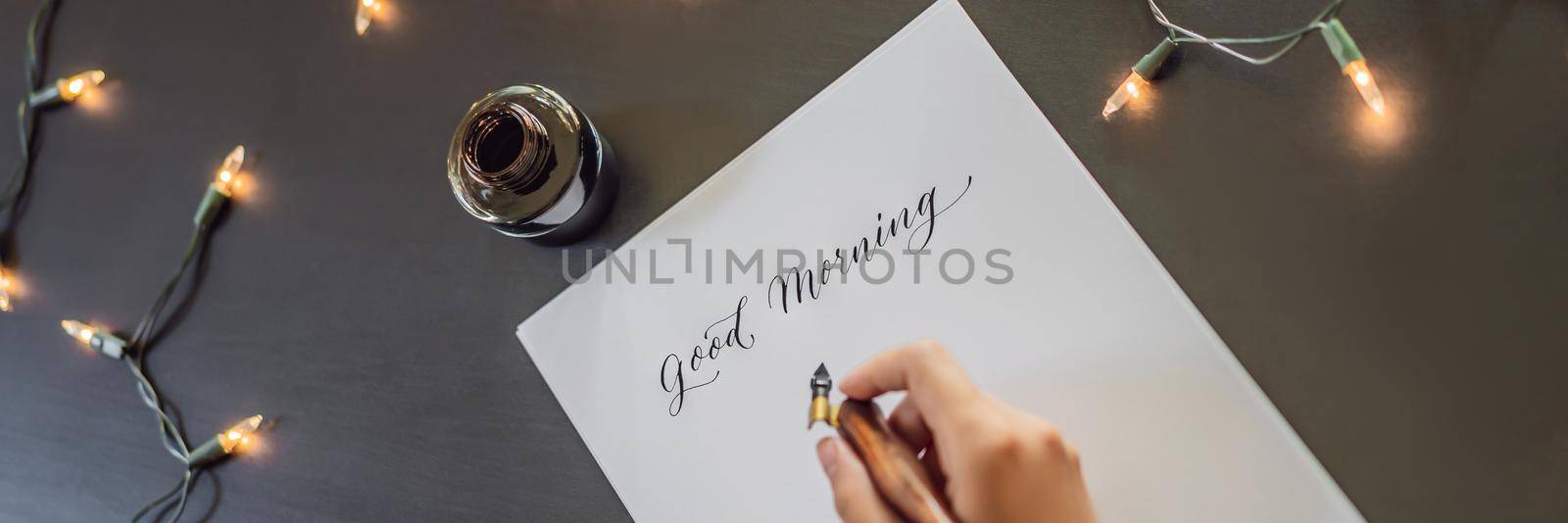 BANNER, LONG FORMAT Good morning. Calligrapher Young Woman writes phrase on white paper. Inscribing ornamental decorated letters. Calligraphy, graphic design, lettering, handwriting, creation concept by galitskaya