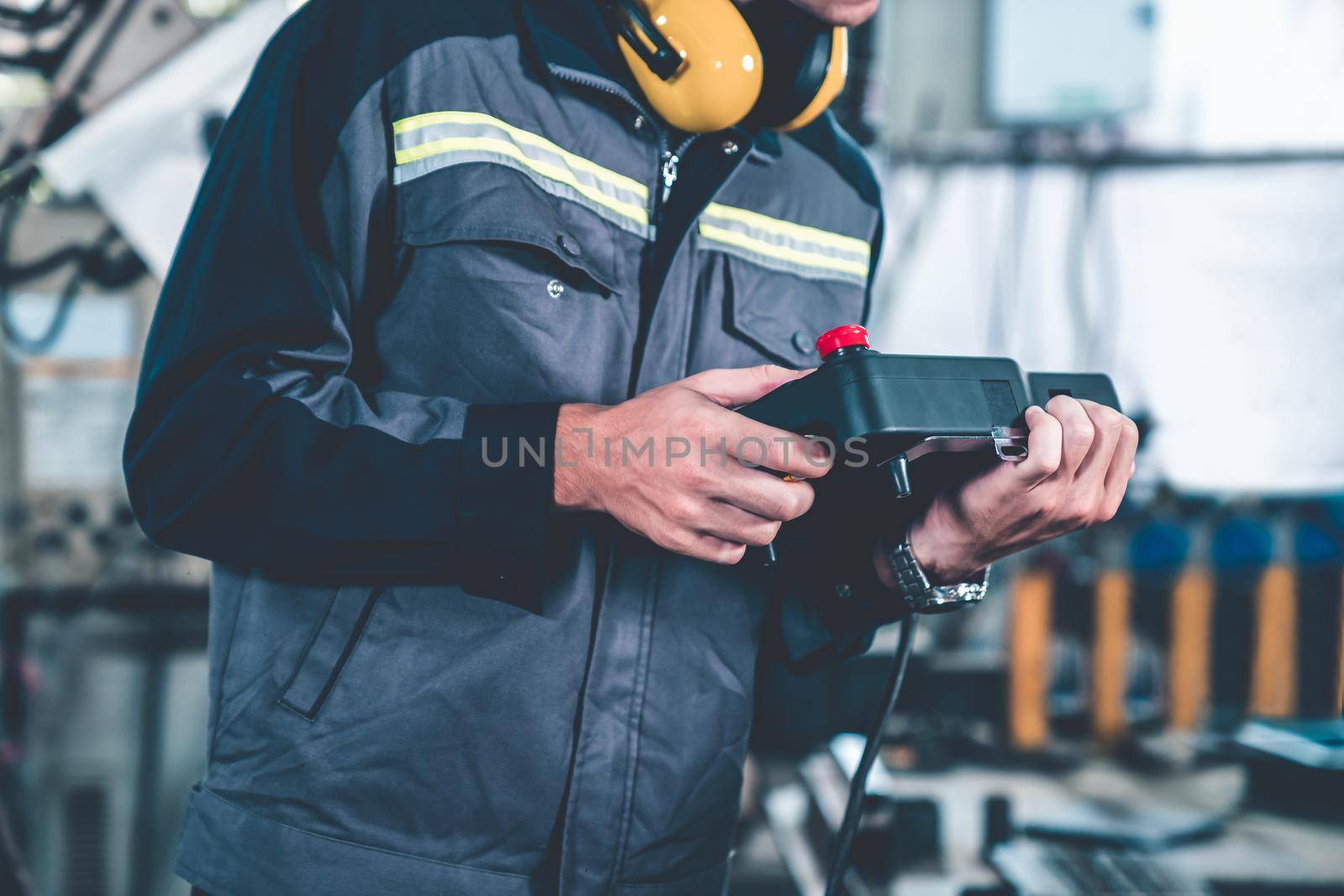 Young factory worker working with adept robotic arm in a workshop . Industry robot programming software for automated manufacturing technology .