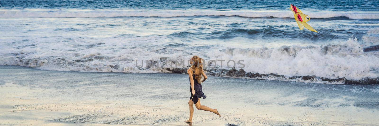 A young woman launches a kite on the beach. Dream, aspirations, future plans. BANNER, LONG FORMAT