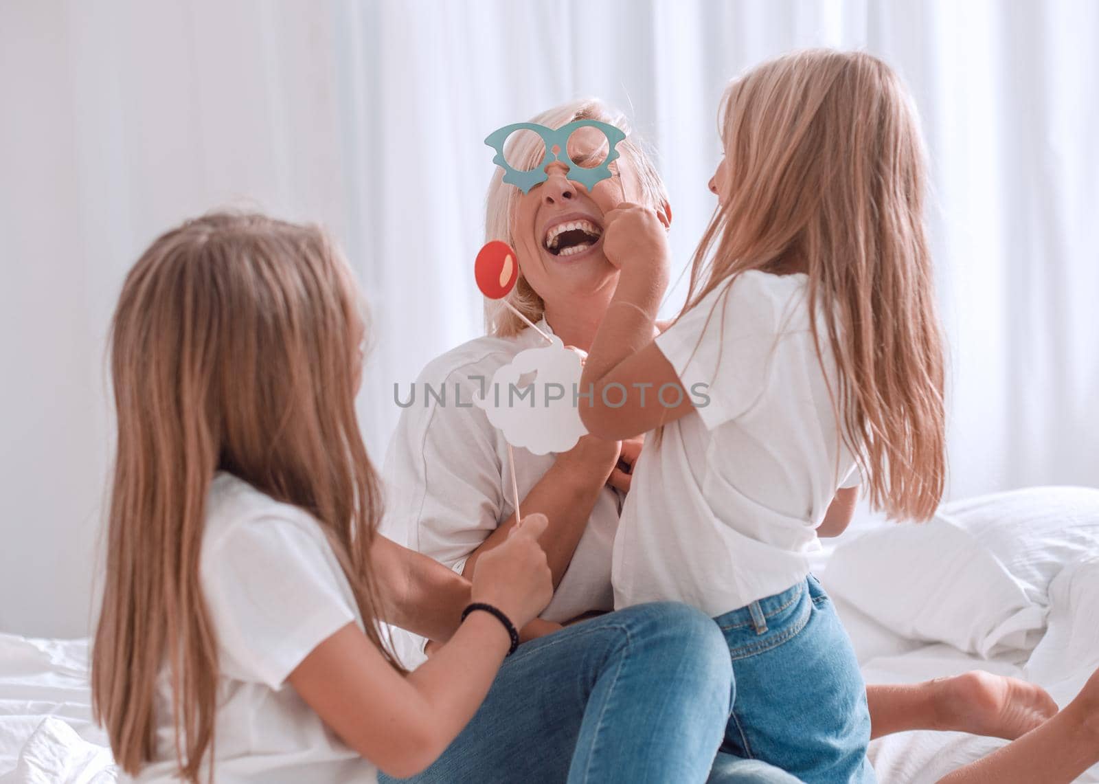 close up. two daughters play with mom sitting on the couch. the concept of family happiness