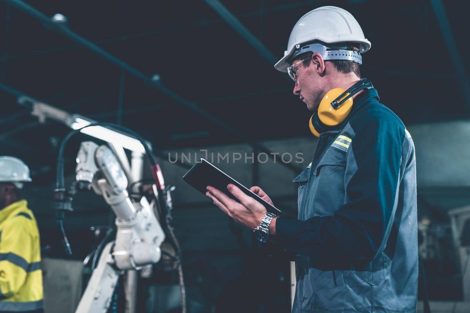 Factory workers working with adept robotic arm in a workshop . Industry robot programming software for automated manufacturing technology .