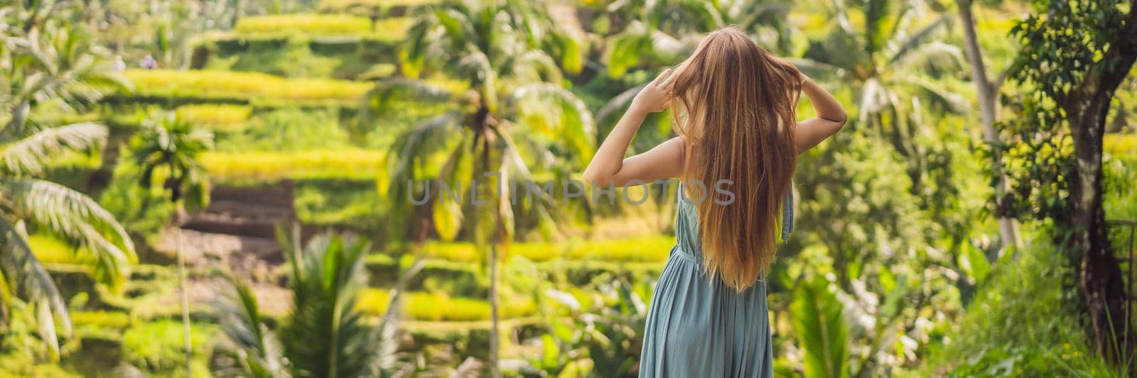 BANNER, LONG FORMAT Beautiful young woman walk at typical Asian hillside with rice farming, mountain shape green cascade rice field terraces paddies. Ubud, Bali, Indonesia. Bali travel concept.