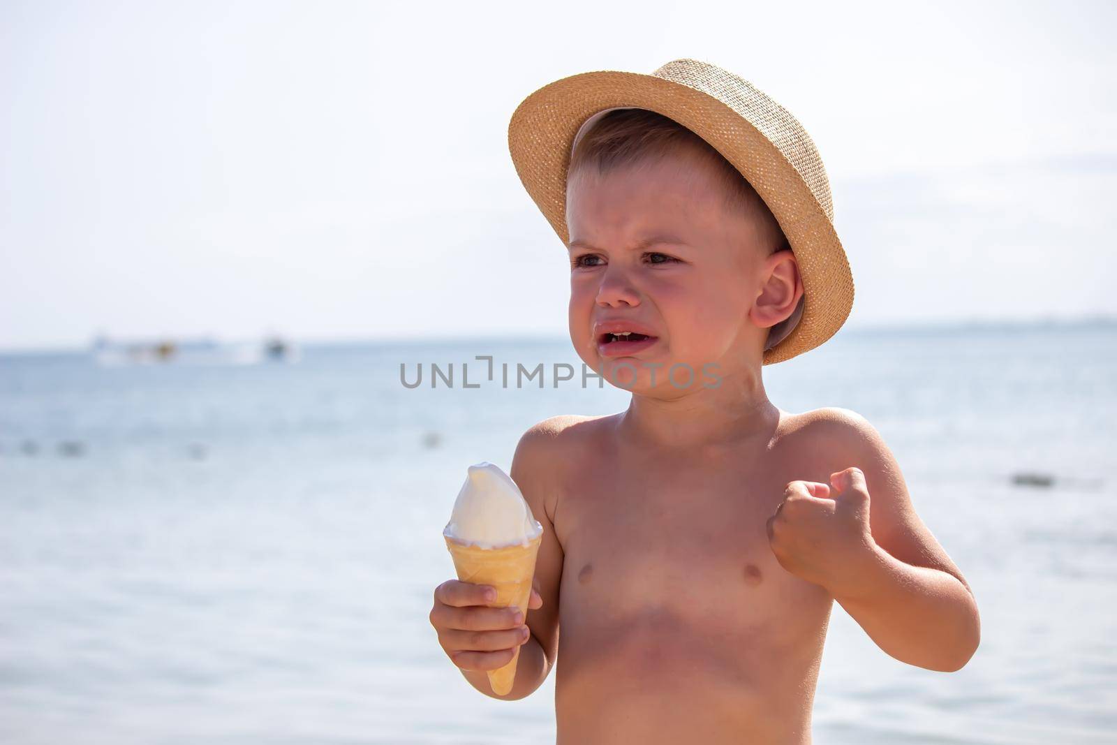 the child cries and eats ice cream on the beach. selective focus