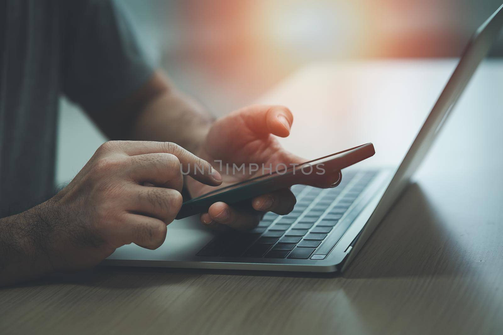 Man using smartphone and working with laptop on table, Business concept smart phone technology conversation conferrence. by Wmpix