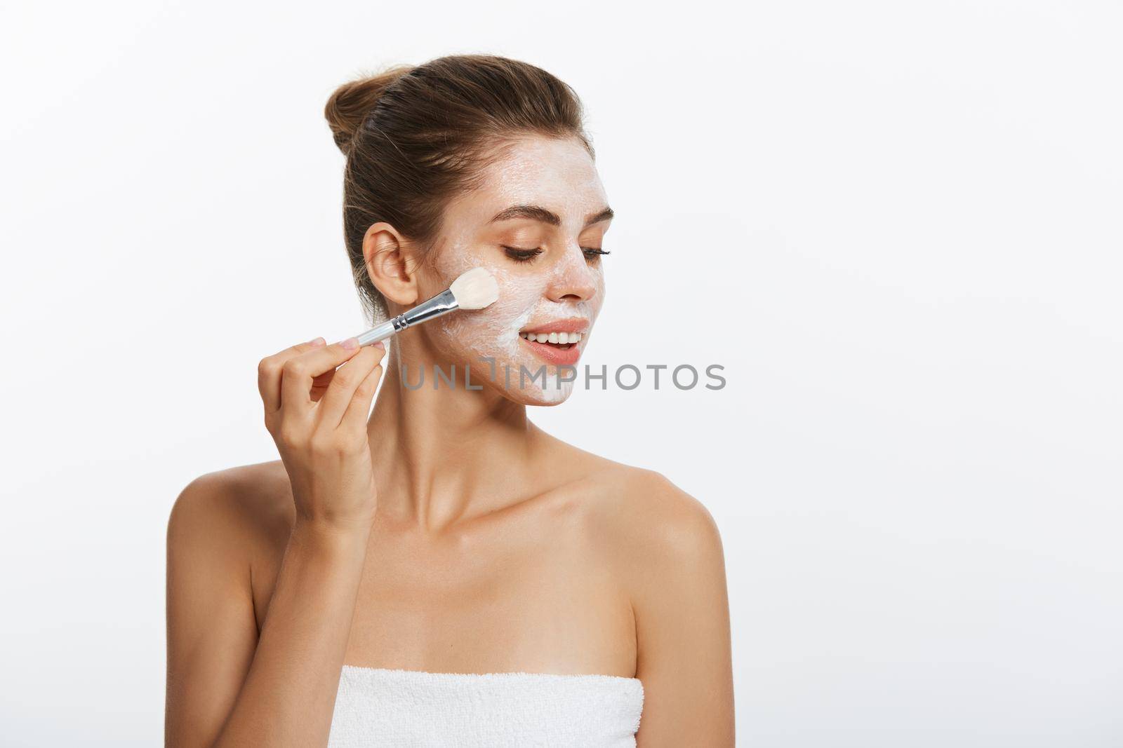Portrait beautiful naked woman apply cosmetic white clay mask on with brush. Isolated on a white background. concept of beauty and health.