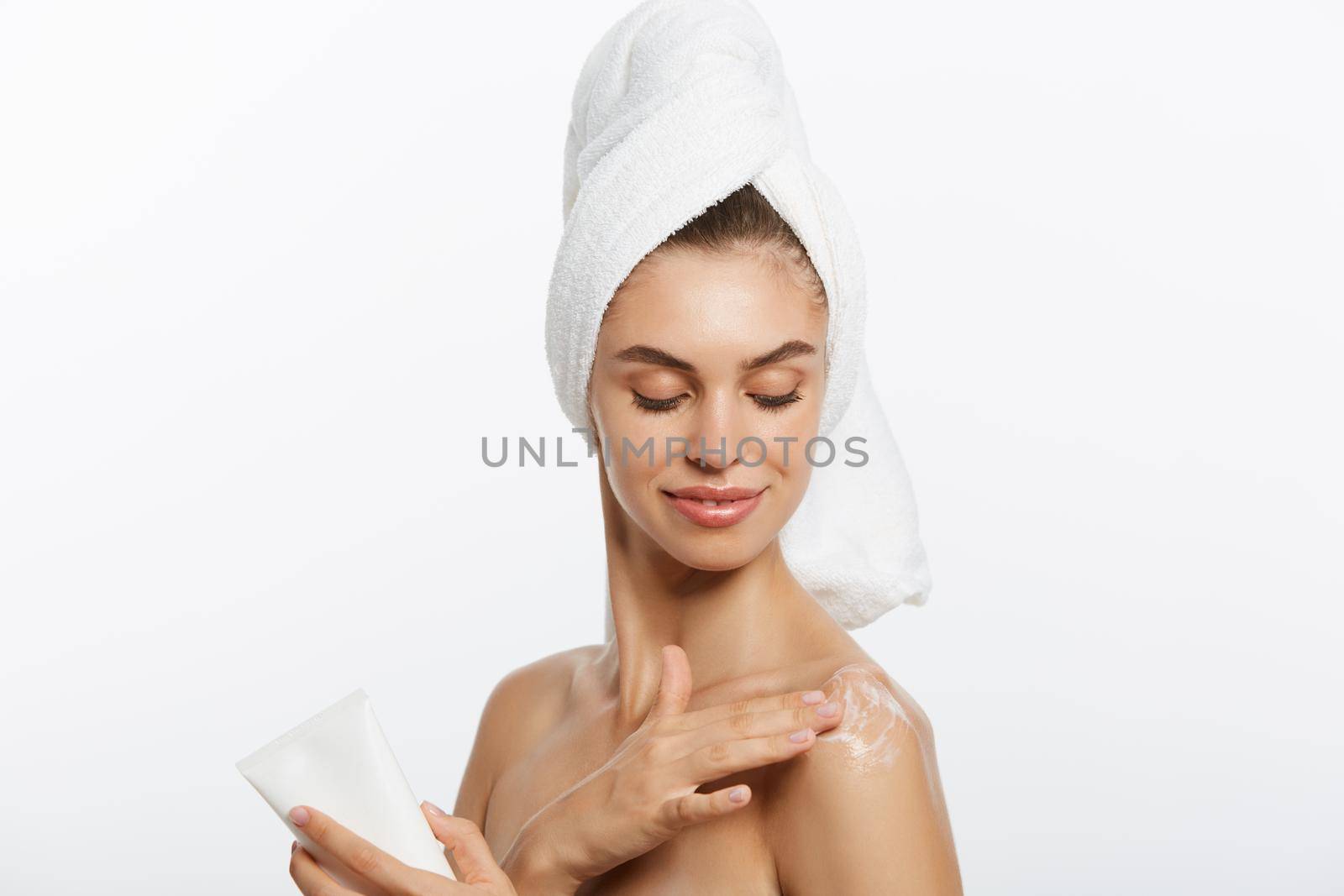 Woman applying cream on shoulder on a white background. by Benzoix