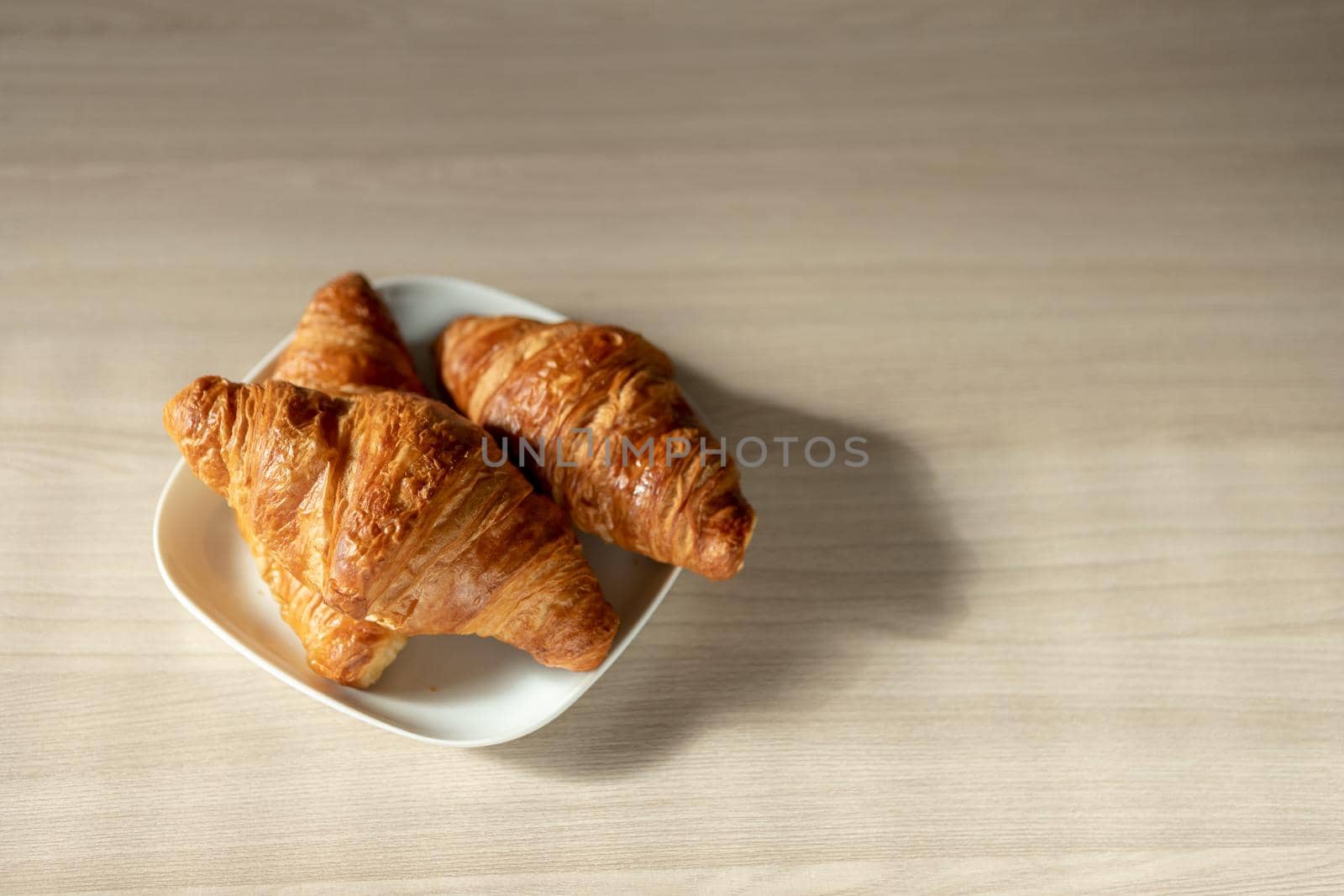 there are three croissants on the table on a white plate for breakfast by bySergPo