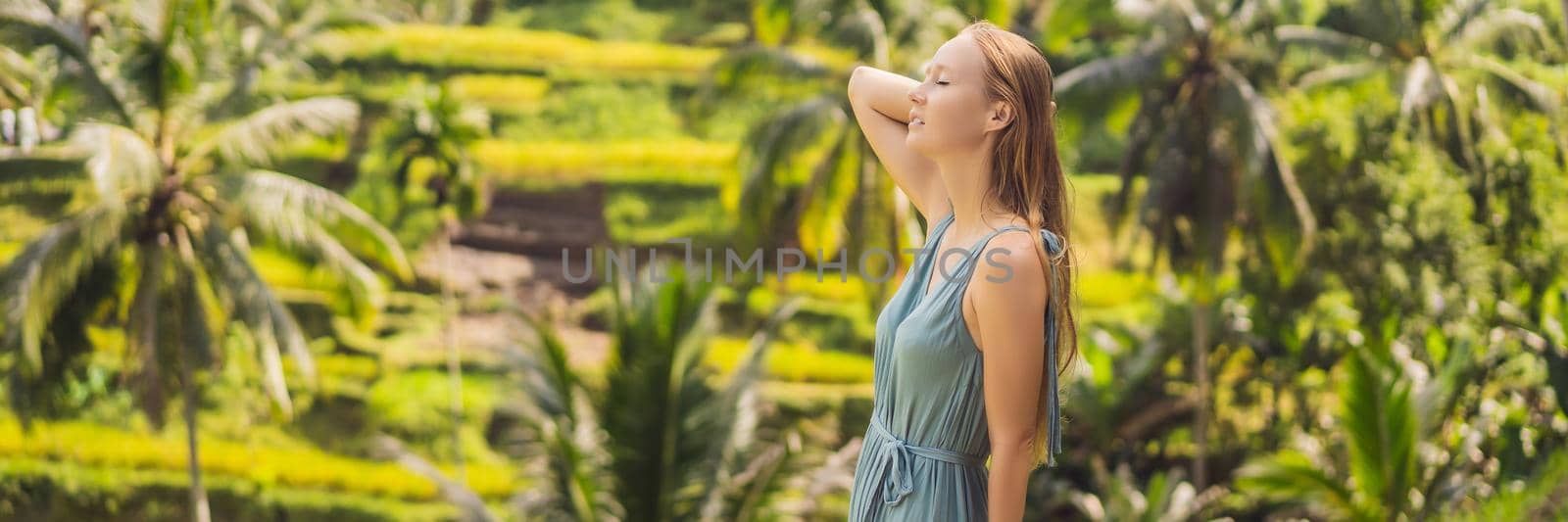 BANNER, LONG FORMAT Beautiful young woman walk at typical Asian hillside with rice farming, mountain shape green cascade rice field terraces paddies. Ubud, Bali, Indonesia. Bali travel concept by galitskaya