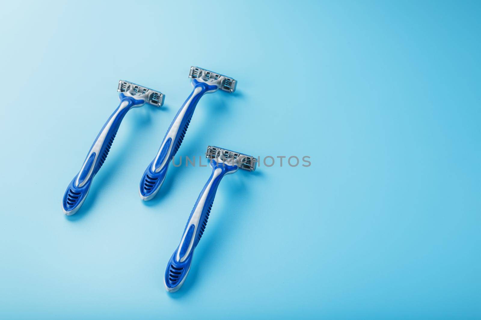 Blue shaving machine with sharp blades on the background of ice cubes close-up. The concept of cleanliness and frosty freshness
