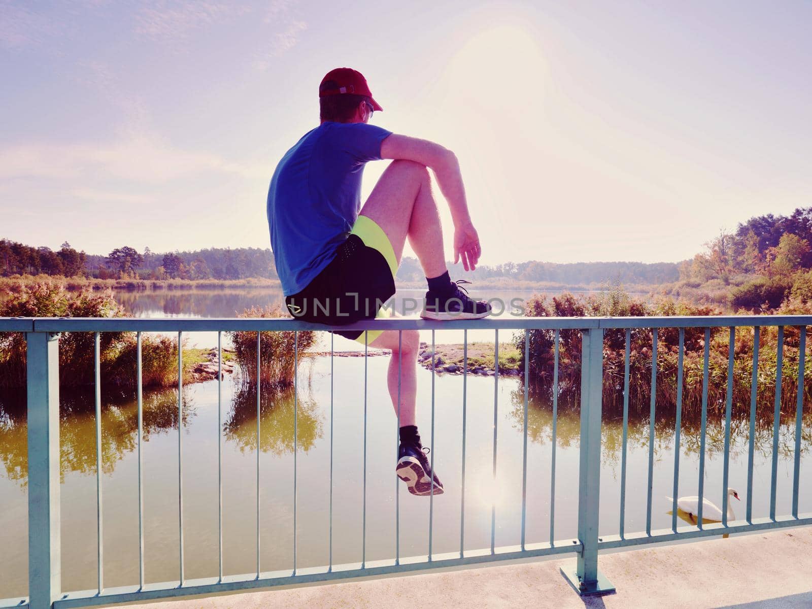 Man thinking. Sportsman in blue t-shirt and black pants  sit on pier by rdonar2