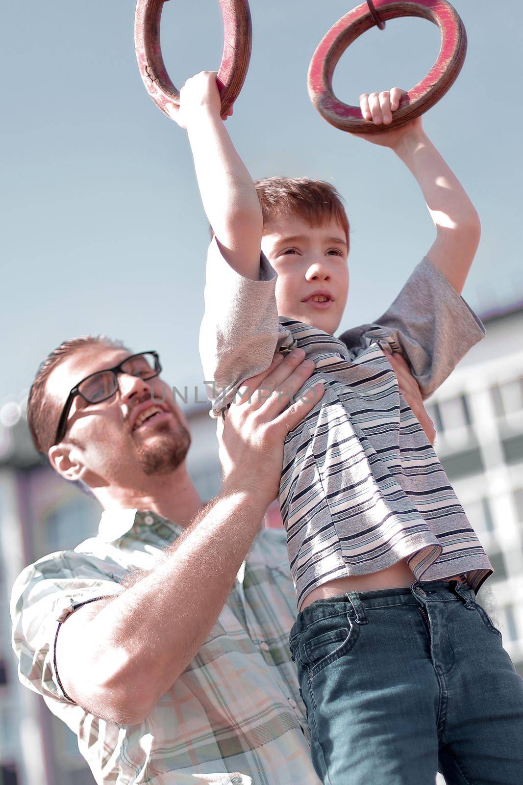 father helps his son to catch up on the bar.the concept of parenting