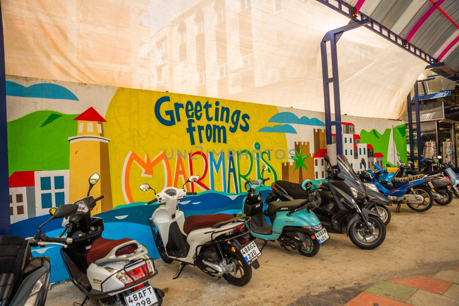 MARMARIS, MUGLA, TURKEY: Motorcycles and scooters are standing at the Drawing on the wall with the inscription Greeting from Marmaris.