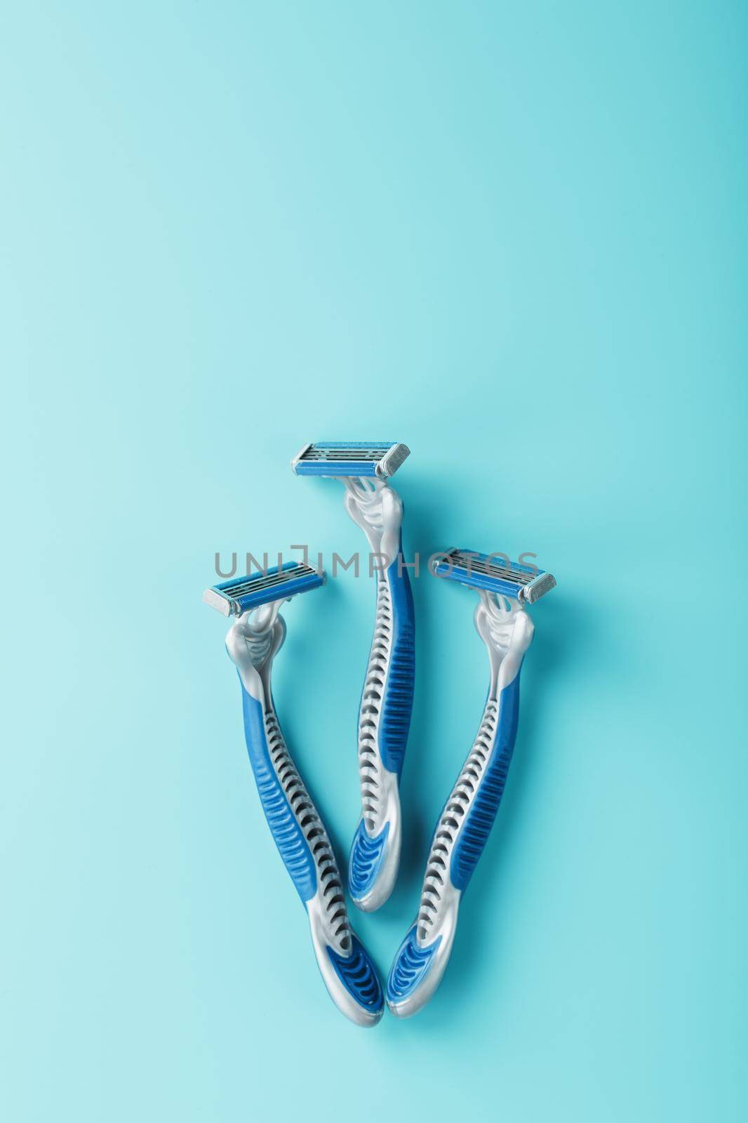 Three shaving machines on a blue background with free space, top view
