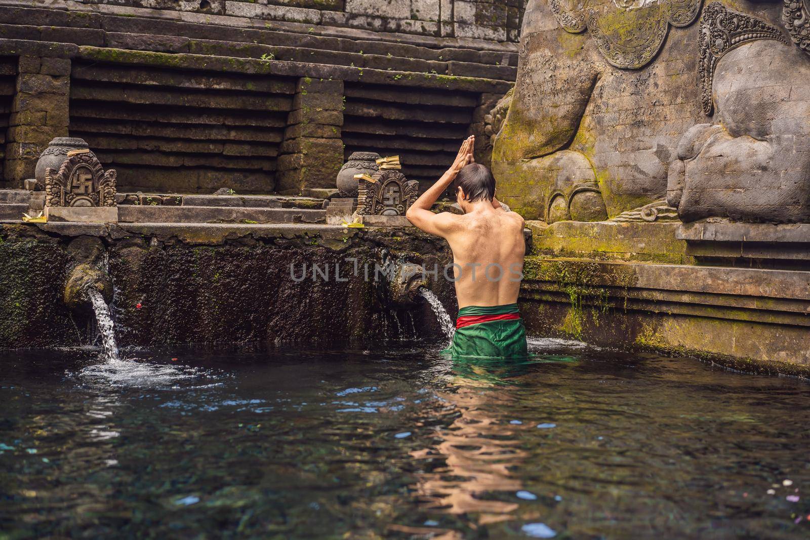 Man in holy spring water temple in bali. The temple compound consists of a petirtaan or bathing structure, famous for its holy spring water by galitskaya