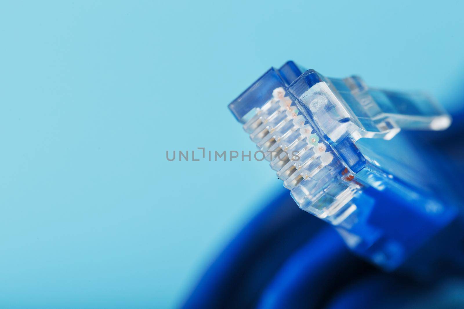 A coil of an Internet network cable for data transmission on a blue background. Patch cord for LAN cable.