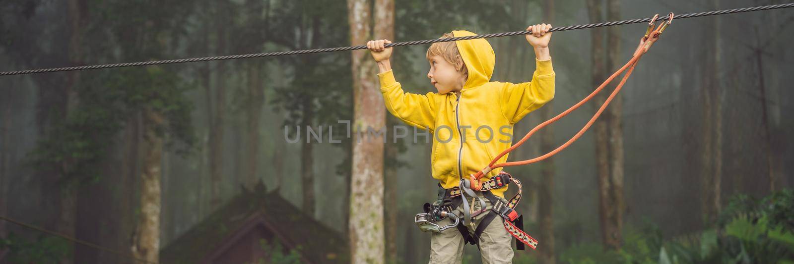 Little boy in a rope park. Active physical recreation of the child in the fresh air in the park. Training for children BANNER, LONG FORMAT by galitskaya