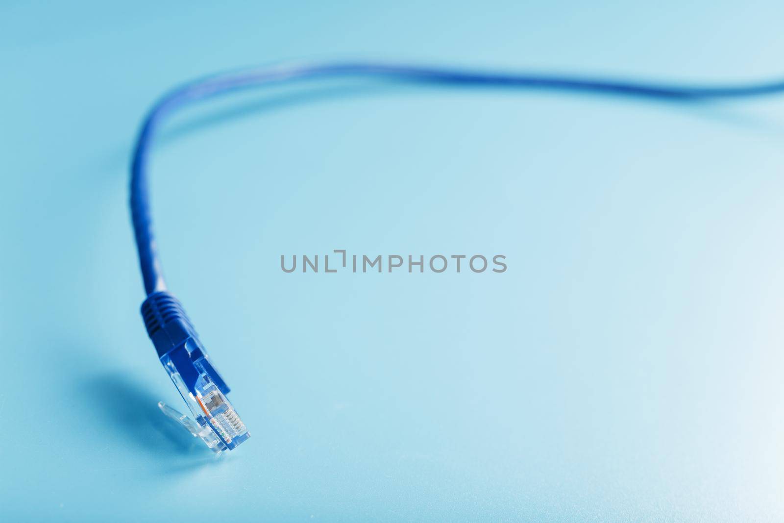 Blue Ethernet Cable Connectors Patch cord cord close-up isolated on a blue background with free space