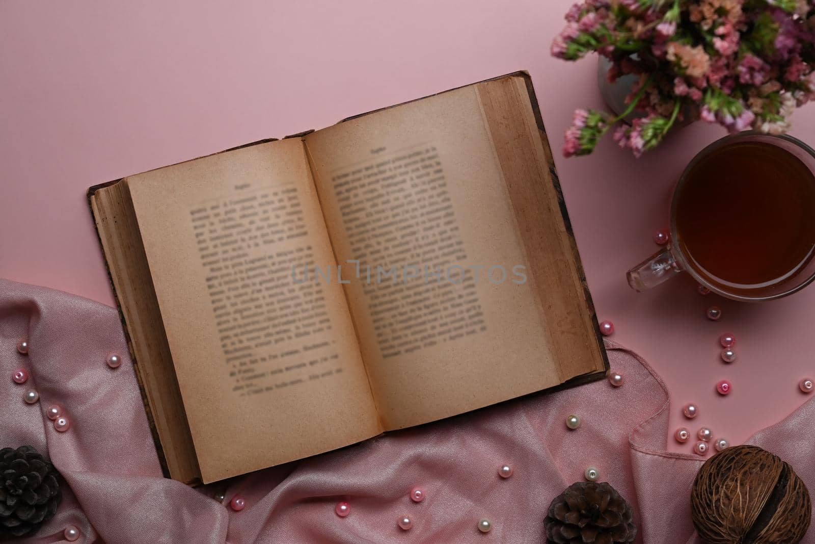 Vintage book, coffee cup and spring flowers on pink background.