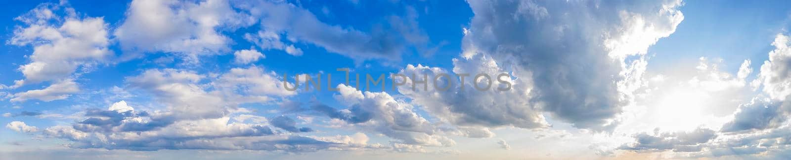 Panoramic view of blue sky with clouds and sun.