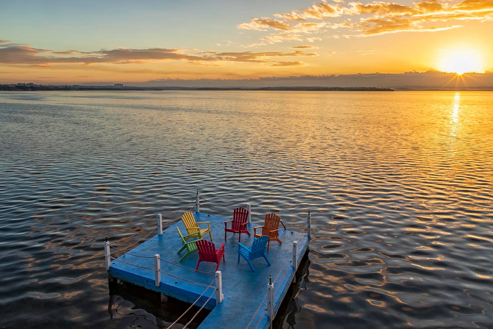 Empty chairs and table on a wooden pier at amazing colorful sunrise in the sea. Time for relax