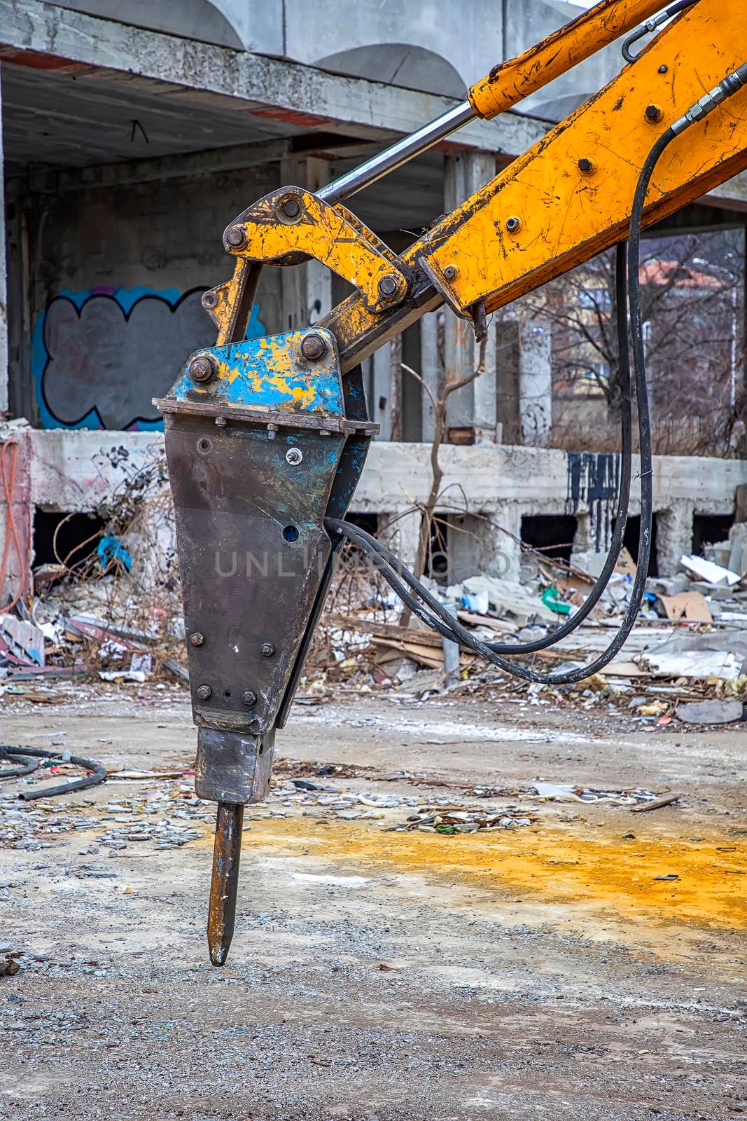 Arm of excavator with hydraulic breaker hammer for the destruction of concrete and hard rock at the construction site. Demolition equipment by EdVal