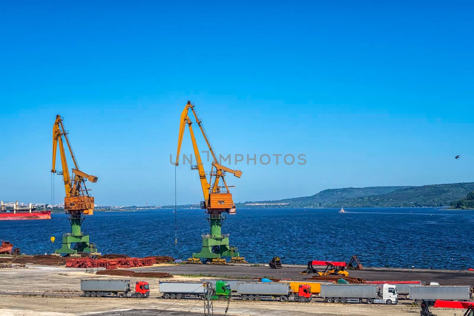 Port cranes ready to load containers from cargo ships. horizontal view by EdVal