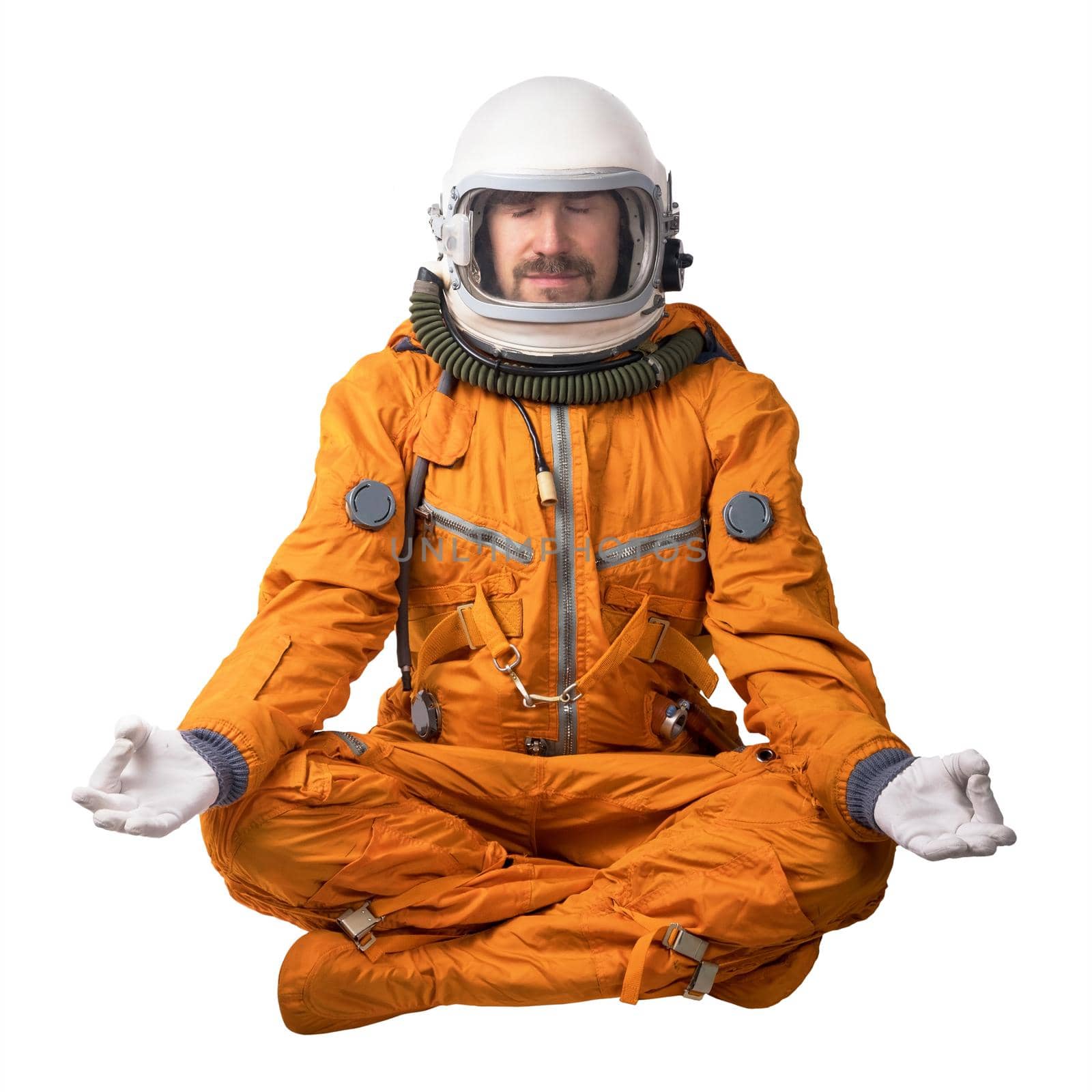 Astronaut wearing orange space suit and space helmet sitting in a lotus pose meditating isolated on a white background. Meditation concept by dmitryz