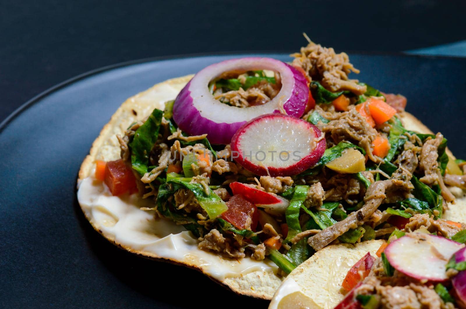Beef salpicon on corn tostadas. Mexican spicy beef steak salad with carrot, olives, chili, onion, lettuce and radish. Delicious Mexican cuisine