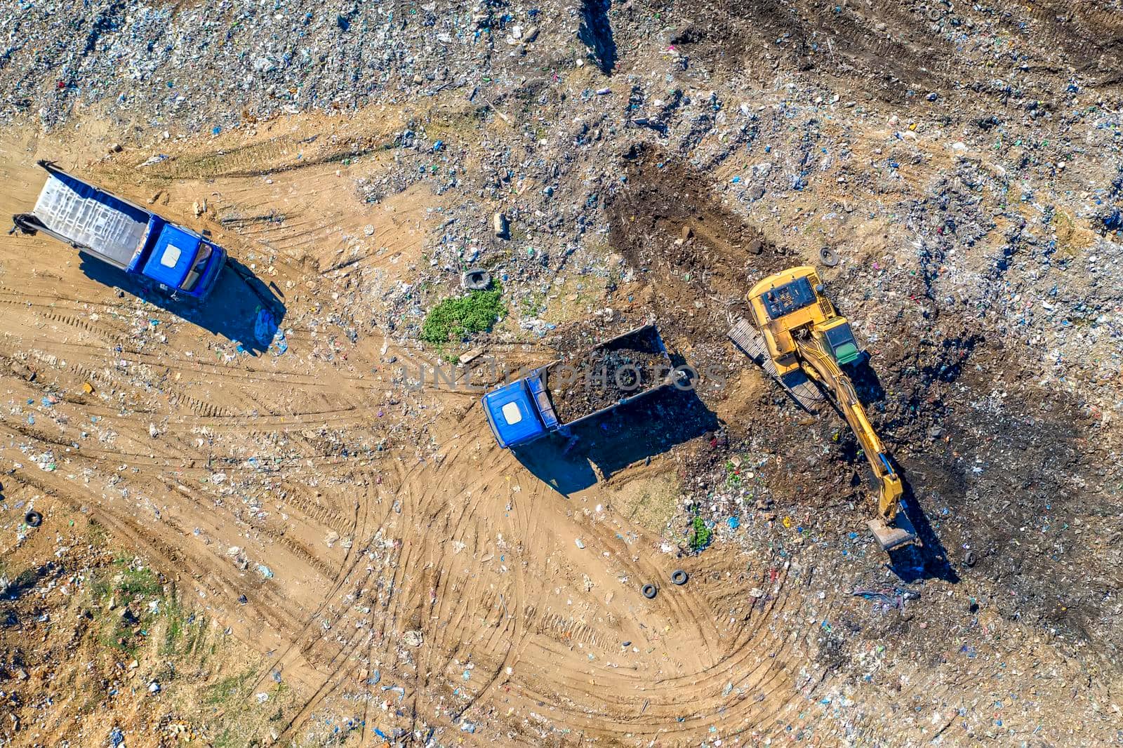 Aerial top view of excavator and dump trucks working at the construction site