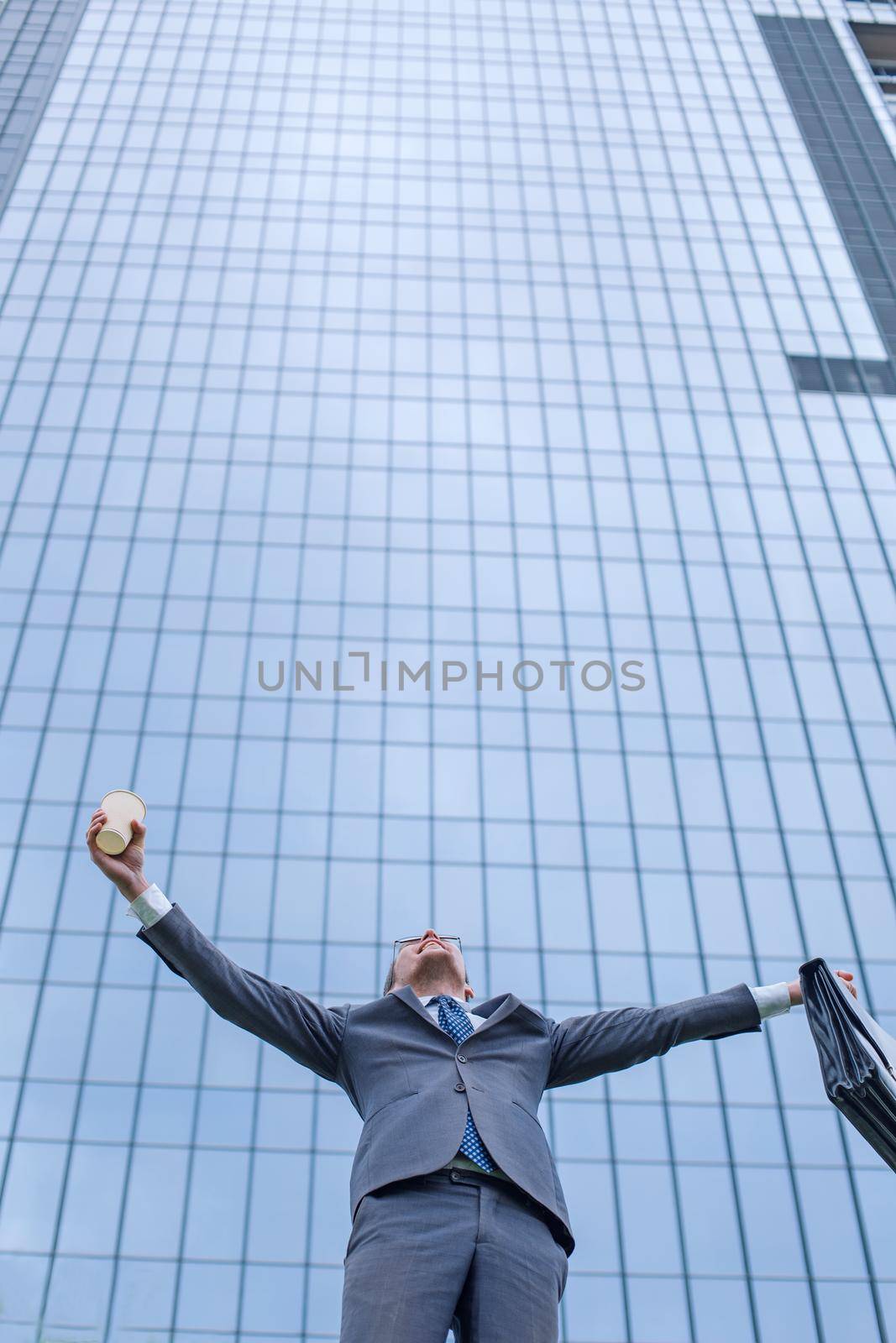 happy business man standing near modern building. photo with copy space