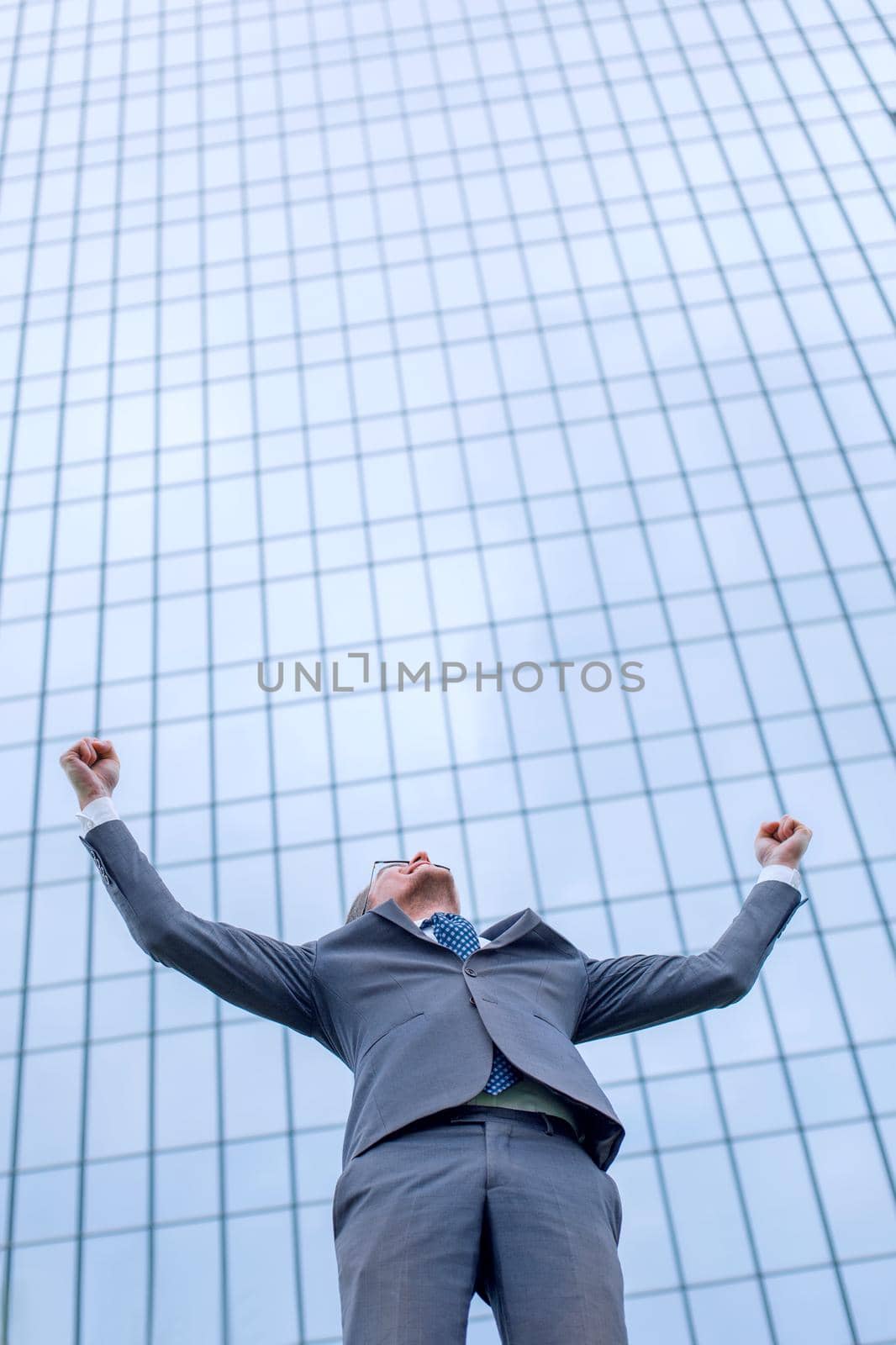 happy young businessman standing on the street and looking up . photo with copy space