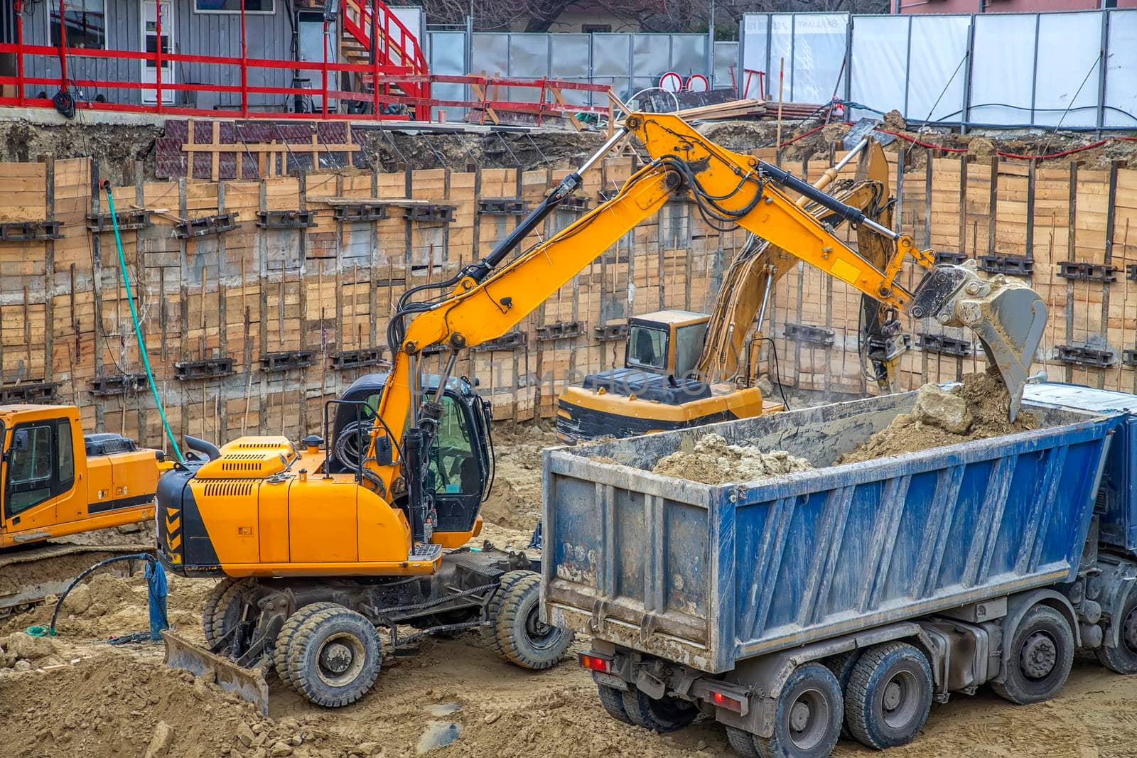 Excavator is loading excavation on the truck. Heavy construction equipment working at the construction site.