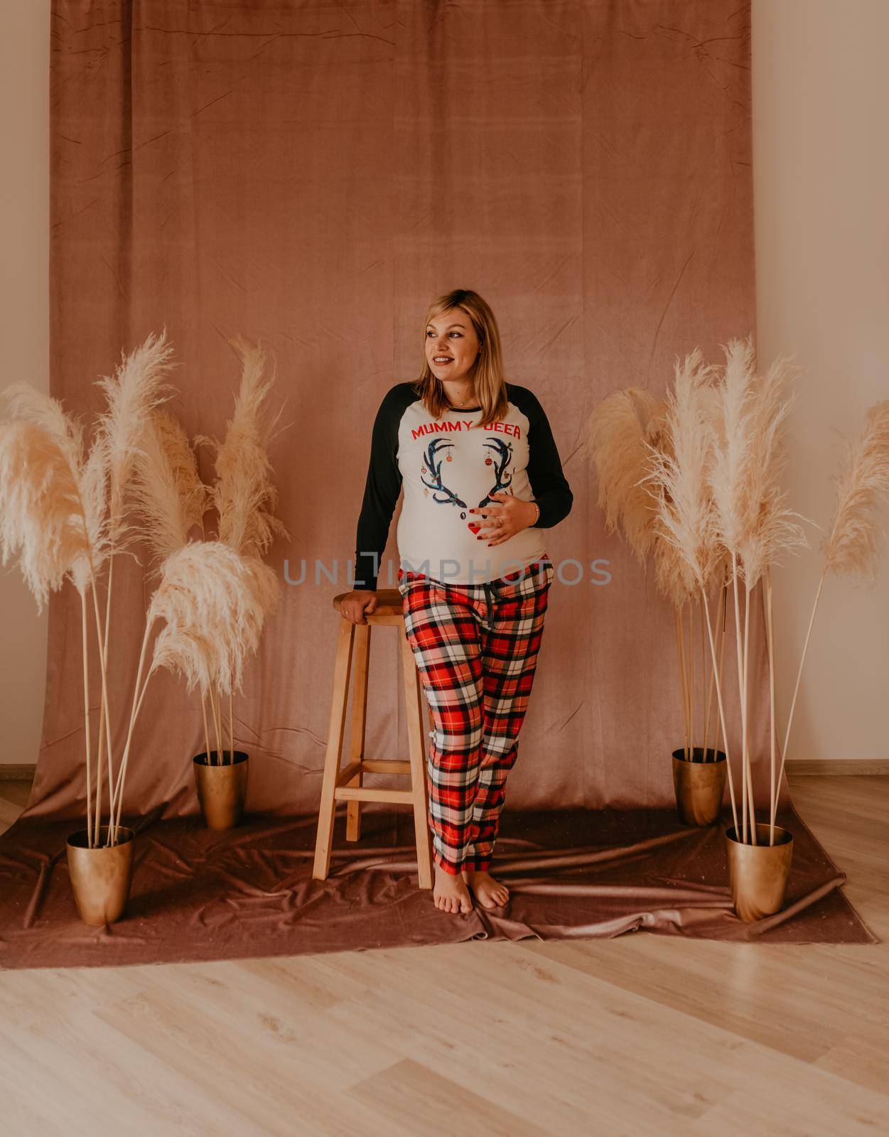 family photo session in studio on beige background with flowers dry reeds. clothes for baby child.pregnant woman in pajamas.Christmas morning.New Year's interior.Valentine's day celebration