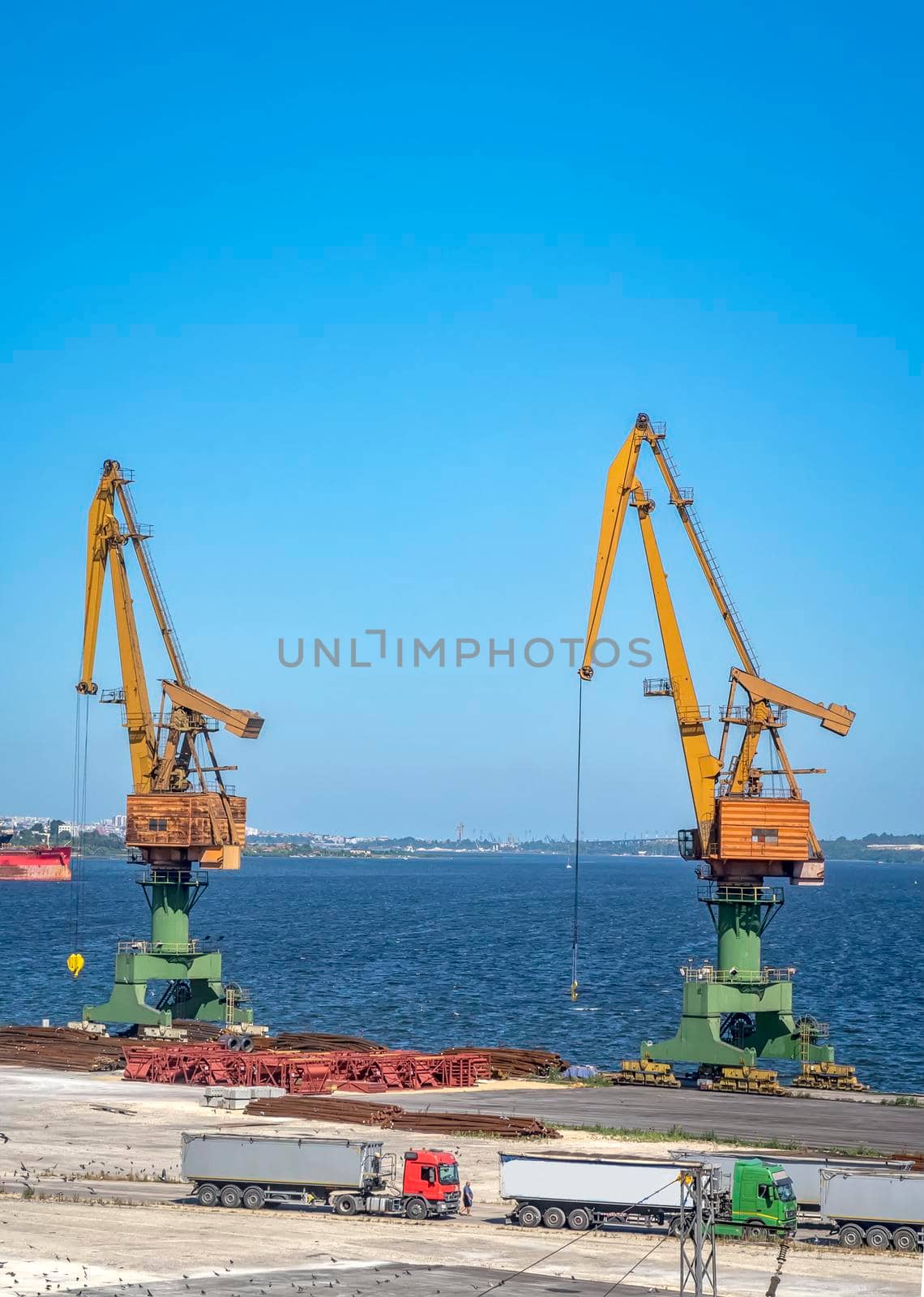 Port cranes ready to load containers from cargo ships. Vertical view