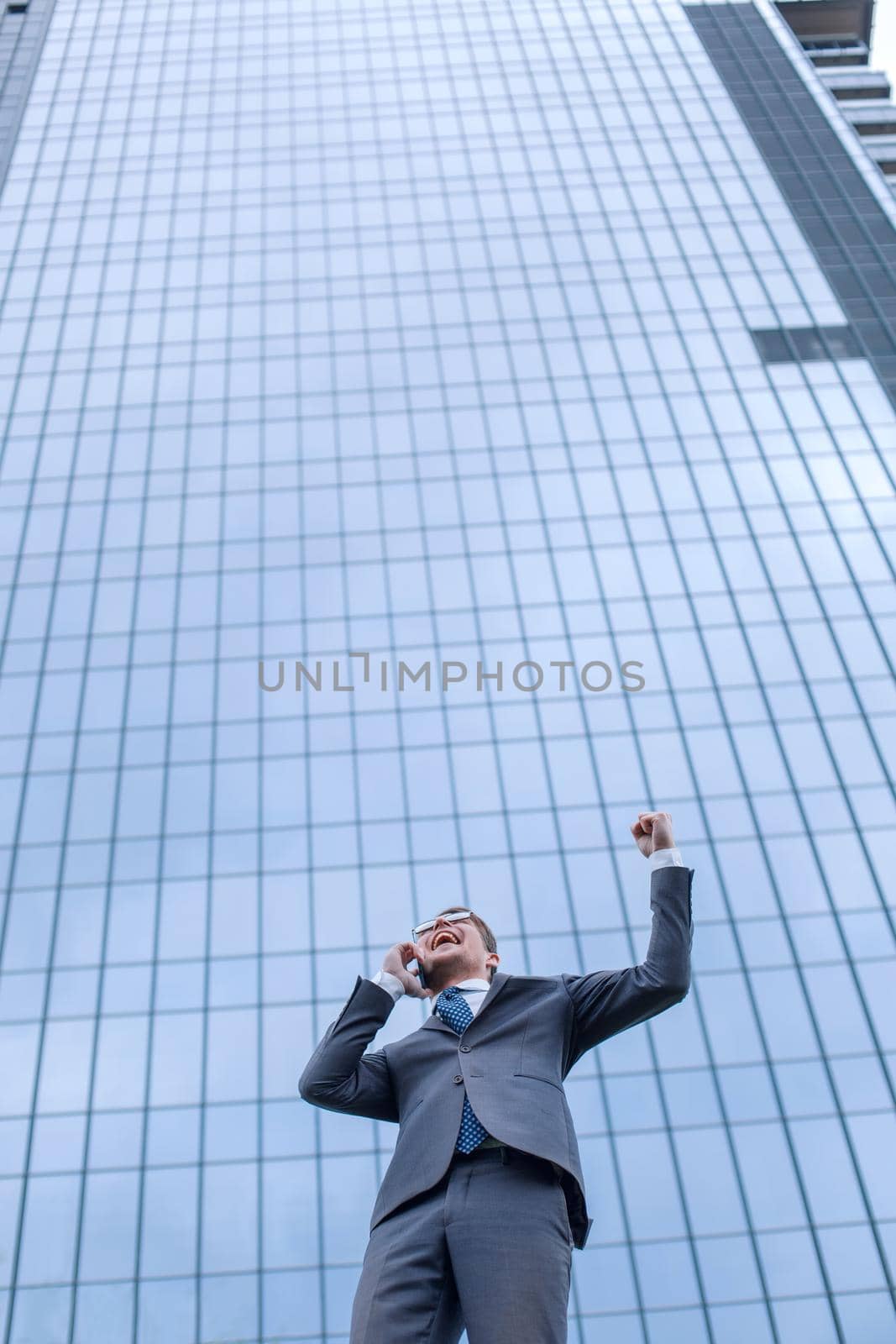 happy businesswoman with smartphone standing next to an office building. photo with copy space
