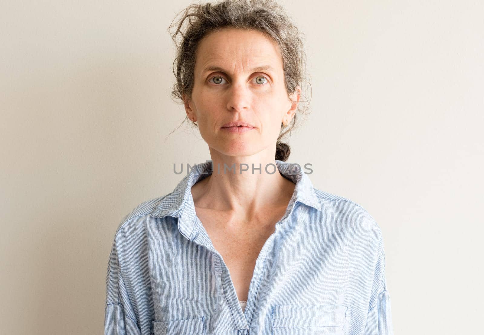 Portrait of natural looking middle aged woman with grey hair and blue shirt