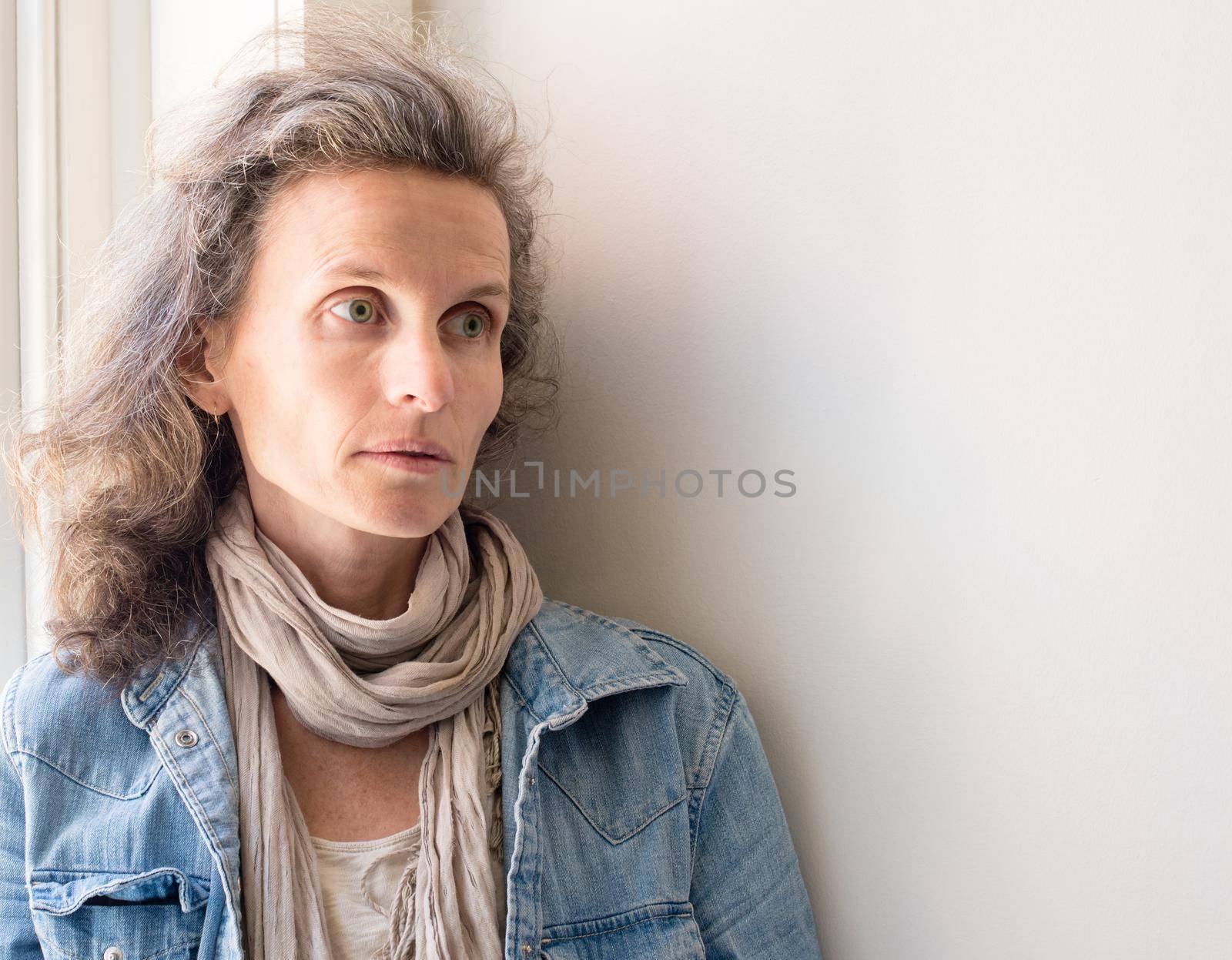 Middle aged woman with grey hair and denim shirt looking sad and anxious by natalie_board
