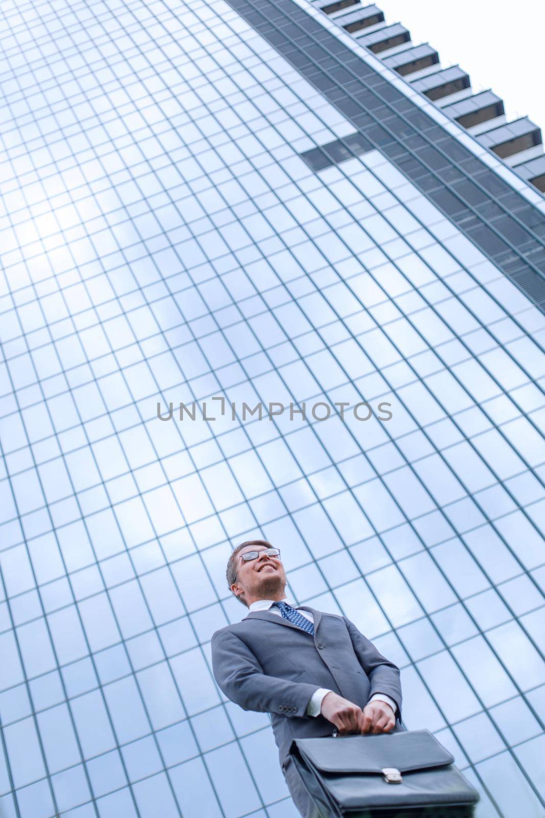 business man with briefcase standing on grass near tall office building by asdf