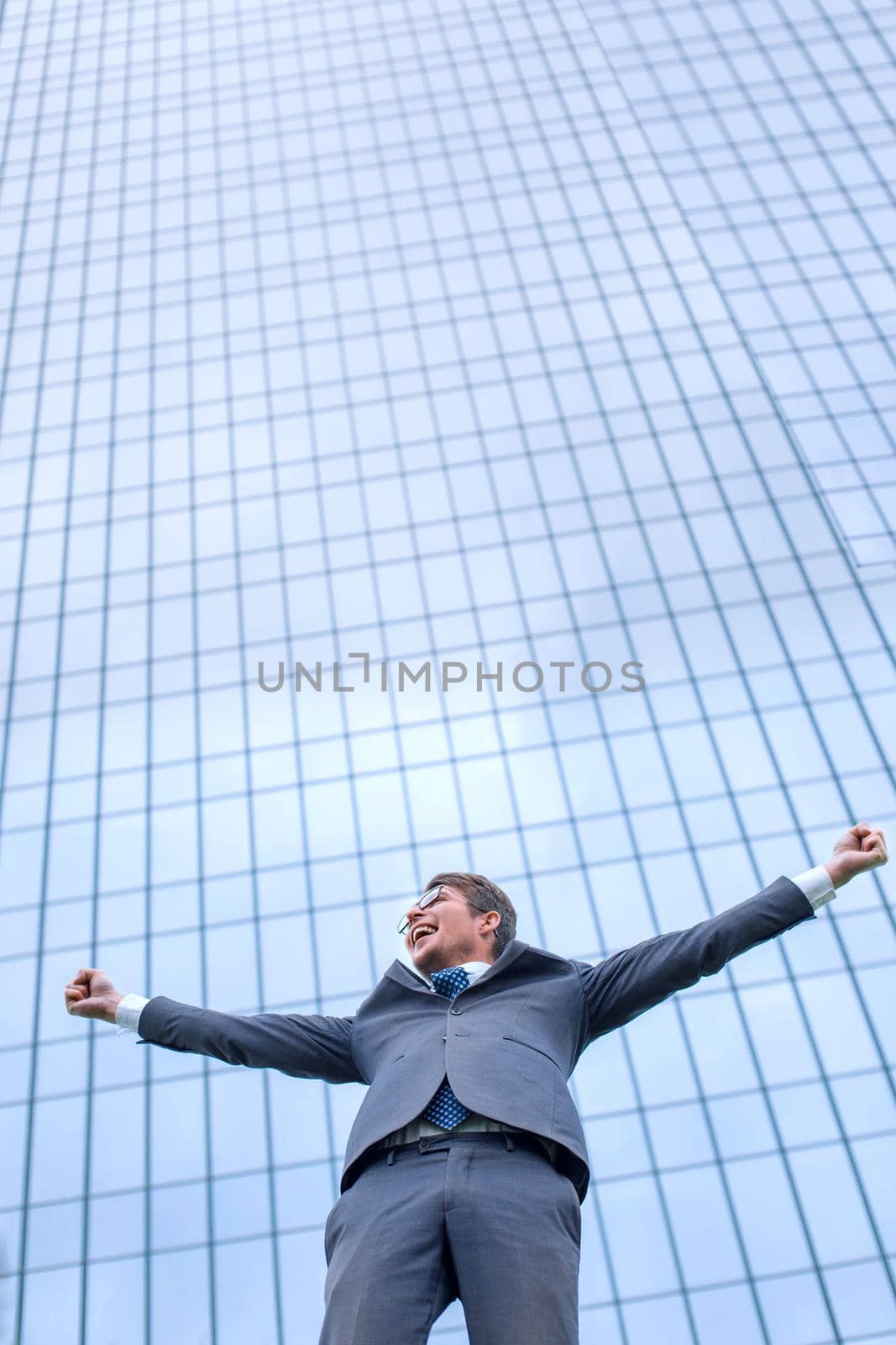 happy young businessman standing on the street in front of the office by asdf