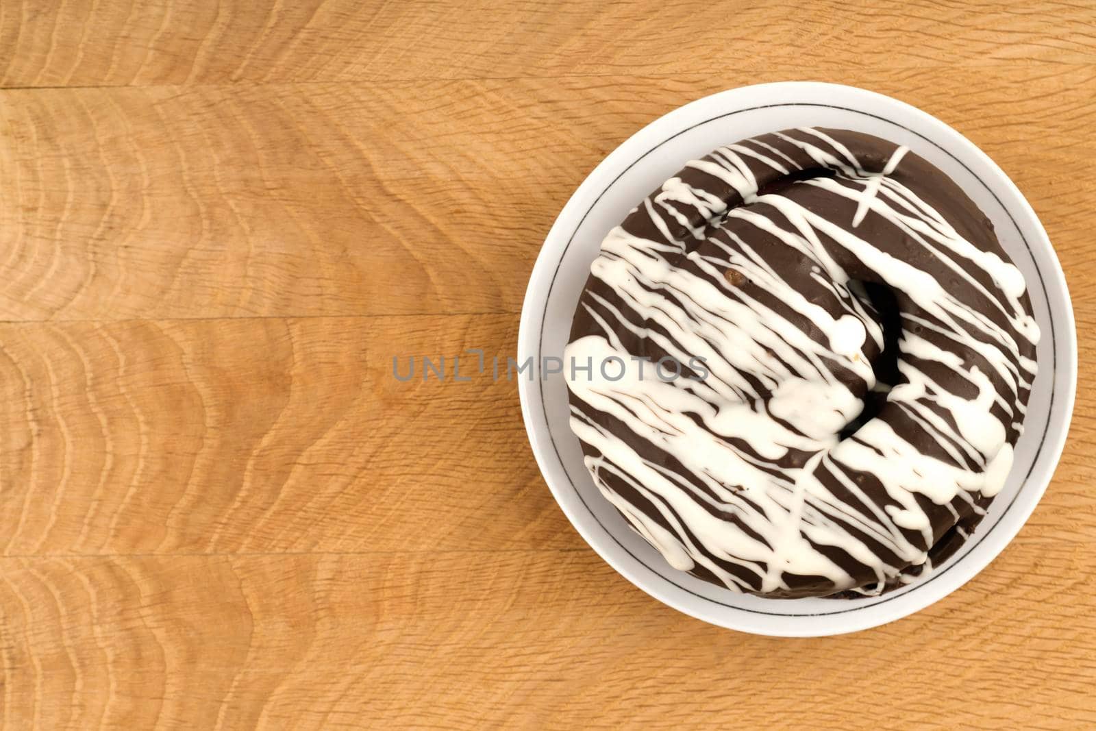 bun covered with chocolate, on a wooden board, close-up