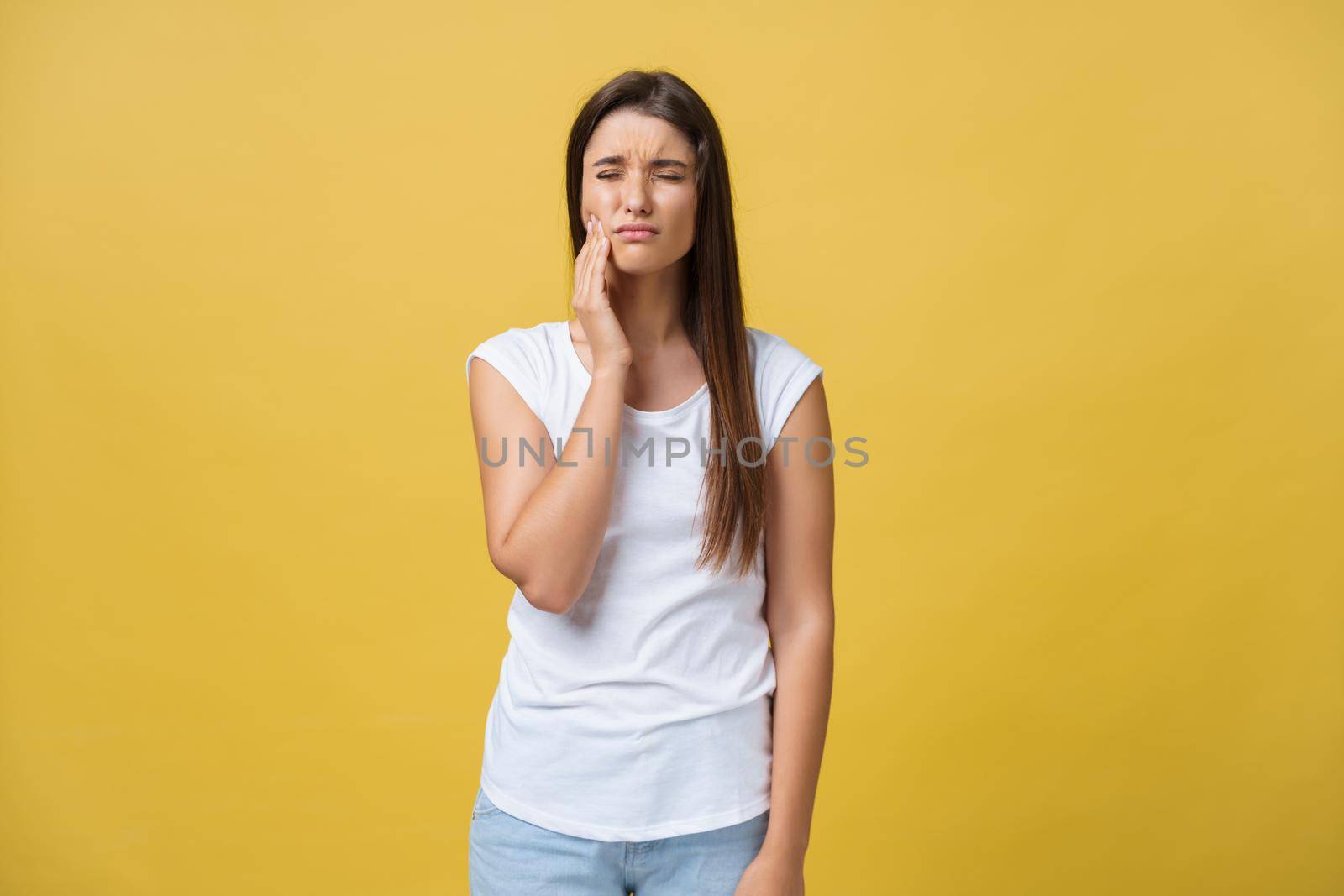 young woman has a toothache, studio photo isolated on a yellow background by Benzoix