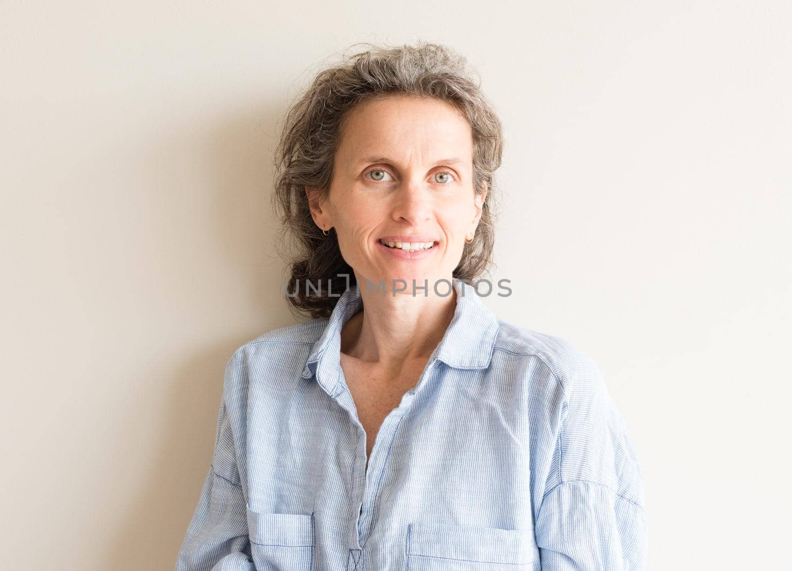 Natural looking middle aged woman with grey hair and blue shirt smiling