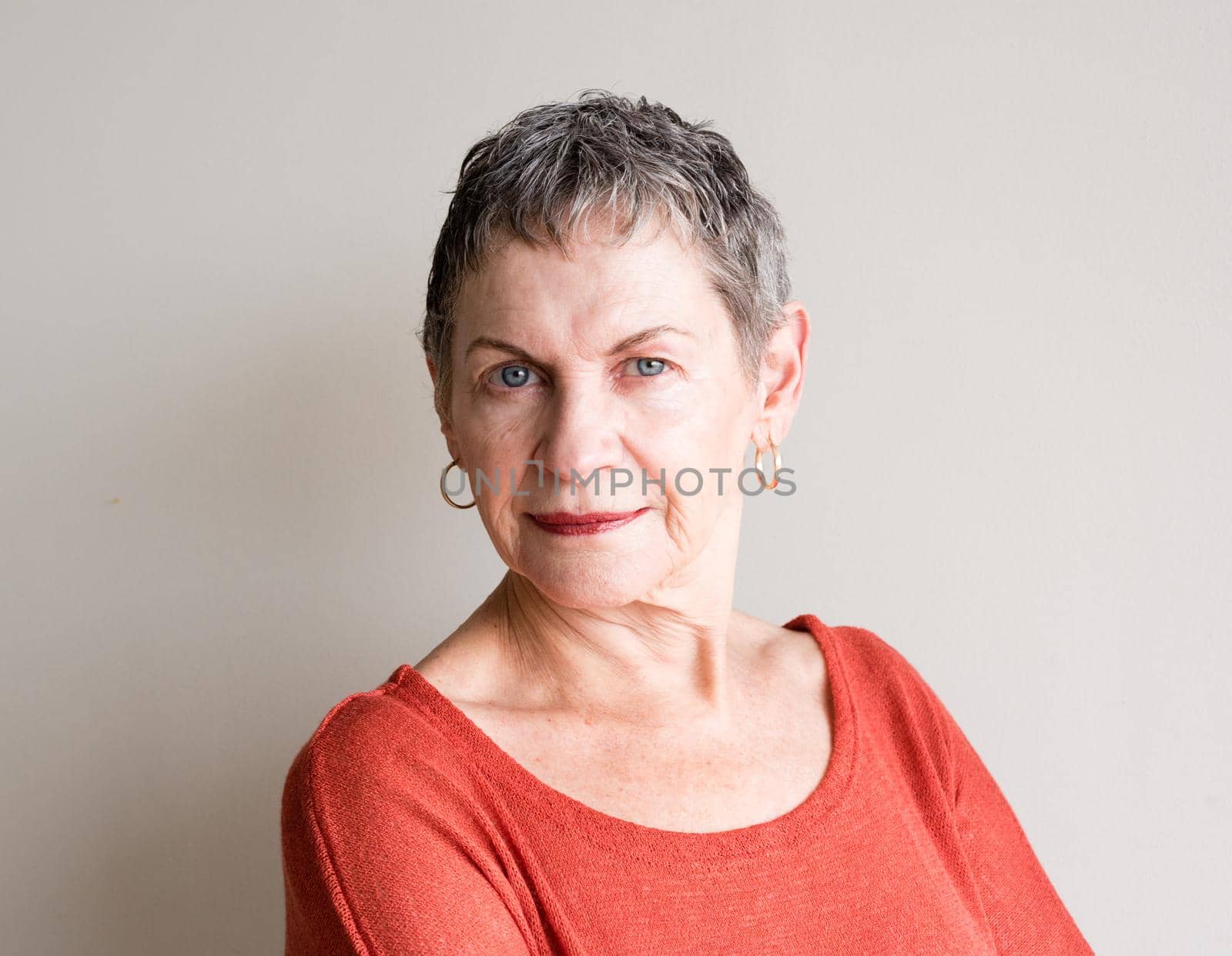 Portrait of older woman with short grey hair and orange top